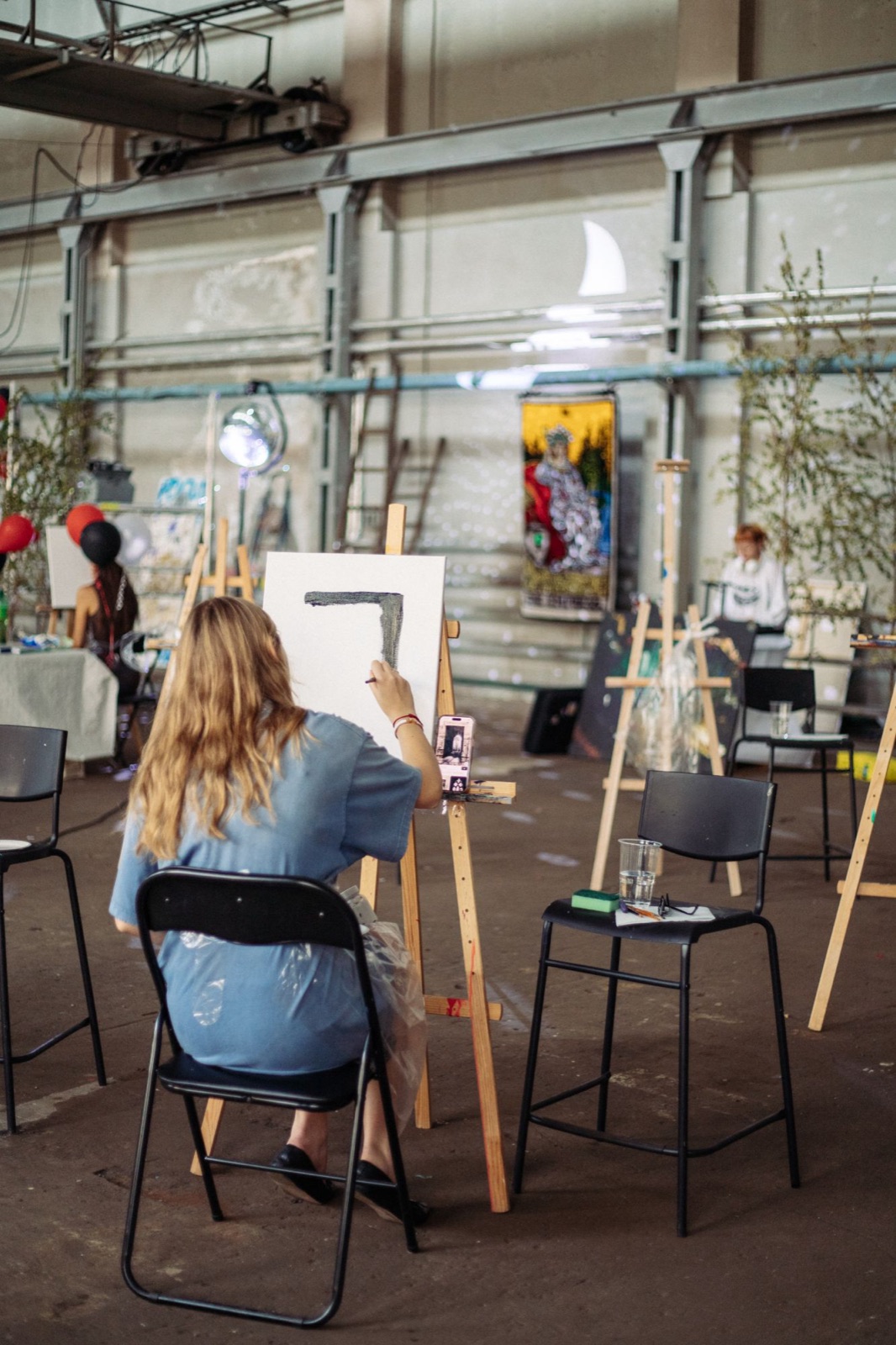 A participant painting at an easel during an Art Cehs workshop