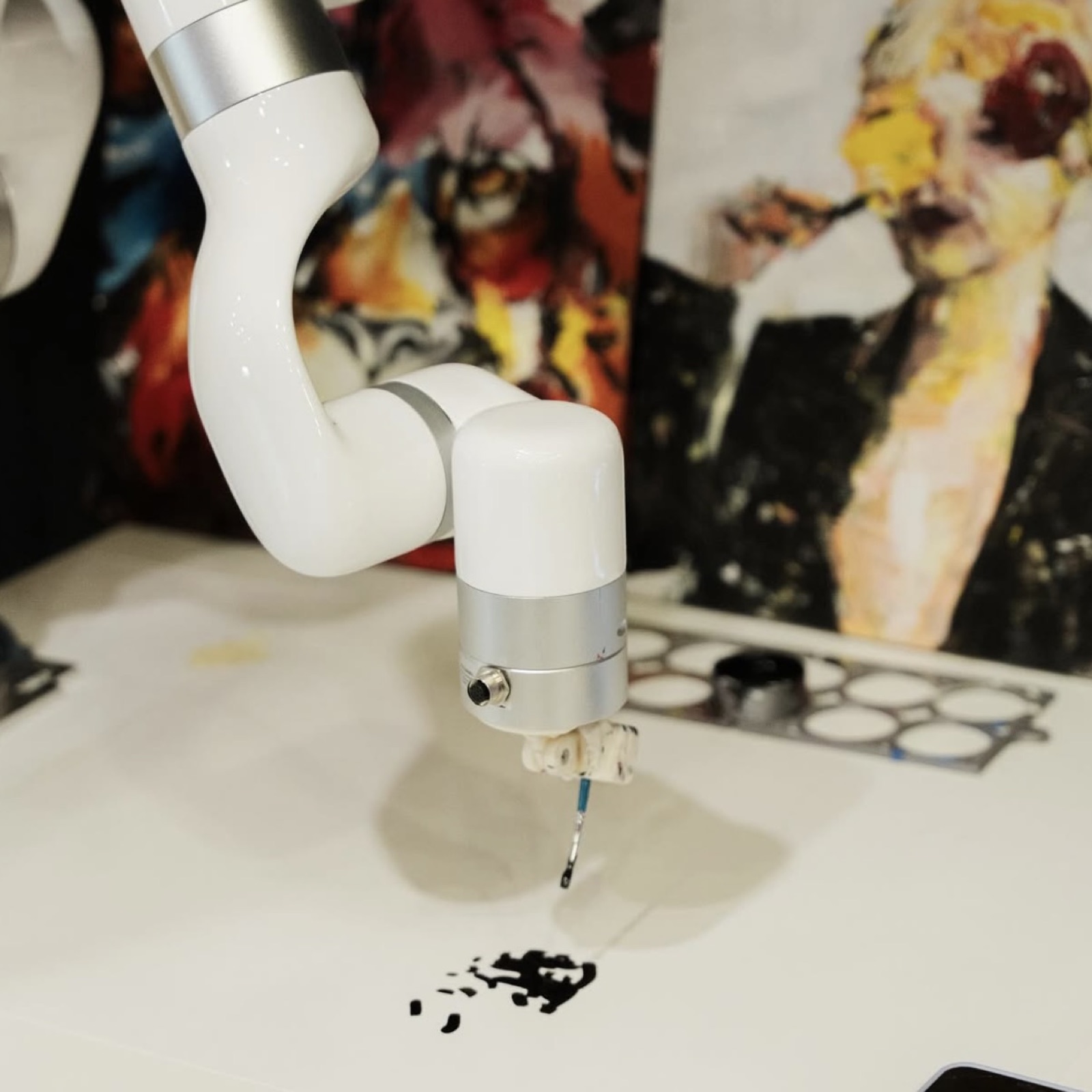 Robotic arm with a brush painting in black ink, finished paintings in the background